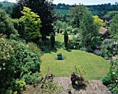 LONG SHOT OF THE GARDEN FROM THE HOUSE WITH 4 TAXUS BACCATA FASTIGIATA  TWO CIRCULAR LAWNS  SHED AND COPPER POT WASHED TORQUOISE. THE WHITE HOUSE  SUSSEX