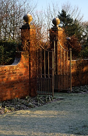 WINTER_SUNLIGHT_SHINES_ON_THE_ORNATE_METAL_GATES_WHICH_DIVIDE_THE_FROST_COVERED_GARDEN_AT_WOLLERTON_