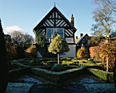 VIEW ACROSS THE FROSTED KNOT GARDEN  PAST TOPIARY ILEX   TOWARDS THE TUDOR HOUSE. WOLLERTON OLD HALL  SHROPSHIRE.
