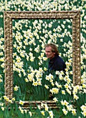 DESIGNER  IVAN HICKS POSES INSIDE AN ORNATE PICTURE FRAME SURROUNDED BY NARCISSUS ICE FOLLIES. GROOMBRIDGE PLACE  KENT.
