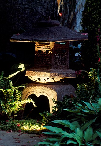 JAPANESE_STONE_LANTERN_LIT_UP_AT_NIGHT__SURROUNDED_BY_HOSTAS_AND_FERNS_IN_THE_ZEN_INSPIRED_GARDEN_DE