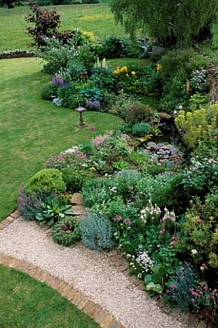 LAUNA_SLATTERS_GARDEN__OXON_THE_POND_AND_LAWN_FROM_THE_HOUSE_WITH_BIRD_TABLE_AND_GRAVEL_PATH