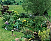 LAUNA SLATTERS GARDEN  OXON: POND WITH BIRD TABLE  HOSTA BLUE MOON  ACER  SILVER BIRCH  LUPINS  IRIS AND COUNTRYSIDE BEYOND