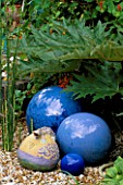 A SALAMANDER JUG FROM BARCELONA AND COBALT BLUE BALLS IN GRAVEL IN ROBIN GREEN AND RALPH CADES SEASIDE STYLE GARDEN  LONDON