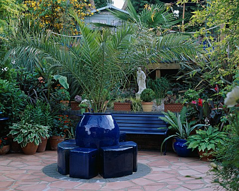 CRAZY_PAVING_PATIO_PAINTED_WITH_SOFT_TERRACOTTA_MASONRY_PAINT_WITH_COBALT_BLUE_POTS__SEAT_AND_FOLIAG