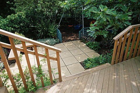 VIEW_ONTO_CHILDRENS_GARDEN_FROM_DECKED_TERRACE_SWINGS_WITH_BARK_BENEATH__BLUE_TRELLIS_SCREENS__PAVIN