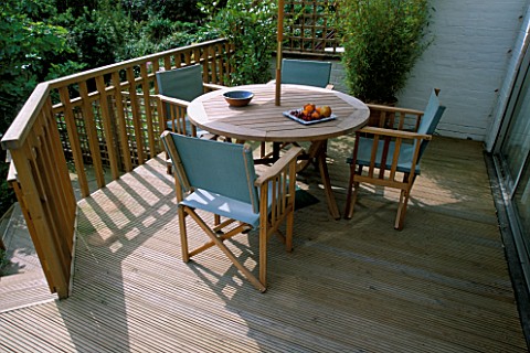 TABLE_AND_CHAIRS_ON_A__DECKED_TERRACE_IN_A_GARDEN_DESIGNED_BY_SARAH_LAYTON