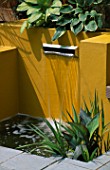LETTERBOX WATER FEATURE WITH RENDERED WALLS PAINTED YELLOW AND HOSTAS. DESIGNER: JOE SWIFT
