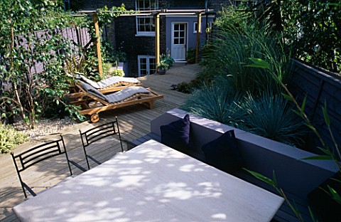GARDEN_WITH_DECKING_DESIGNED_BY_JOE_SWIFT_AND_THAMASIN_MARSH_VIEW_ACROSS_STONE_TABLE_AND_CHAIRS_TO_W