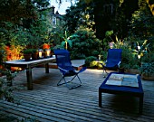 DECKED TERRACE WITH LIGHTING: BLUE DECK CHAIRS  BLUE TABLE  WOODEN TABLE WITH CANDLES  BAMBOO (MUSA BASJOO) AND AGAVE. LIGHTING BY GARDEN & SECURITY LIGHTING