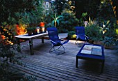 DECKED TERRACE WITH LIGHTING: BLUE DECK CHAIRS  BLUE TABLE  WOODEN TABLE WITH CANDLES  BAMBOO (MUSA BASJOO) AND AGAVE. LIGHTING BY GARDEN & SECURITY LIGHTING