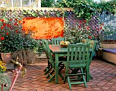 PATIO GARDEN: GREEN WOODEN TABLE AND CHAIRS WITH LILAC TRELLIS  ABSTRACT ORANGE PAINTING BY CLIVE NICHOLS  DAHLIAS BISHOP OF LLANDAF  DAVID HOWARD AND ELLEN HOUSTON