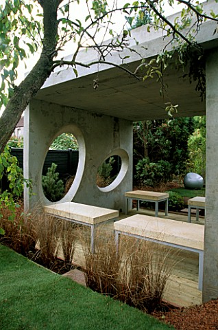 CONCRETE_ROOM_WITH_OVAL_WINDOWS__DECKED_TERRACE_AND_CONCRETE_AND_METAL_SEATS_DESIGNER_DIARMUID_GAVIN