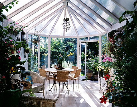 TABLE_AND_CHAIRS_IN_CONSERVATORY_WITH_VIEW_OF_LISETTE_PLEASANCES_GARDEN_OUTSIDE