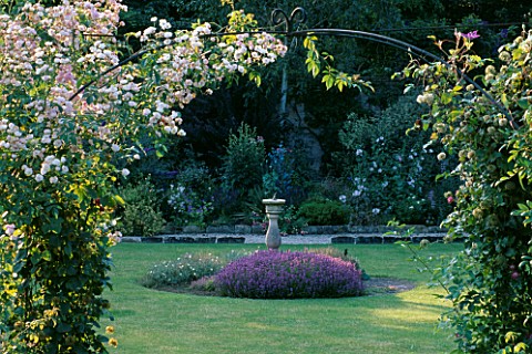 EASTLEACH_HOUSE_GARDEN__GLOUCESTERSHIRE_SUNDIAL__PINKS__THYME_AND_ROSE_ARCH_OF_PRINCES_LOUIS