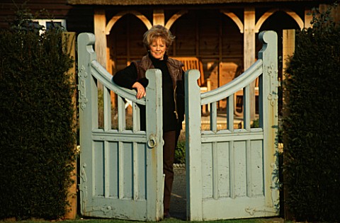 LADY_FARM__SOMERSET__IN_WINTER_JUDY_PEARCE_LEANS_AGAINST_A_BLUE_GATE_ON_THE_UPPER_LAWN