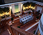 MODERN ROOF GARDEN WITH DECKING  GLASS WATER FEATURE  CLIPPED BOX  STANDARD PHOTINIAS  SILVER TABLE AND CHAIRS. DEVELOPMENT BY CANDY BROTHERS:LIGHTING:LIGHTING DESIGN INTERNATIONAL