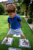 WILLIAM PLAYS ON THE HOPSCOTCH SLABS MADE WITH CEMENT AND WHITE AND BLACK PEBBLES