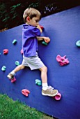 WILLIAM CLIMBS ON THE CLIMBING WALL  IN CLARE MATTHEWS GARDEN  READING