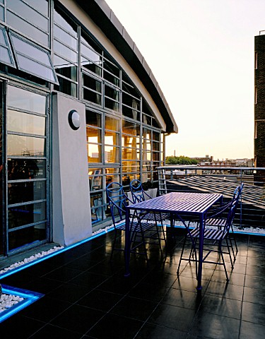 ROOF_GARDEN_DESIGNED_BY_STEPHEN_WOODHAMS_BLACK_SLATE_TERRACE_WITH_TABLE_AND_CHAIRS_AND_NEON_STRIP_LI