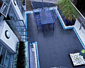 ROOF GARDEN DESIGNED BY STEPHEN WOODHAMS: BLACK SLATE TERRACE WITH METAL TABLE AND CHAIRS AND WATER FEATURE. NEON STRIP LIGHTING. GARDEN DESIGNED BY STEPHEN WOODHAMS