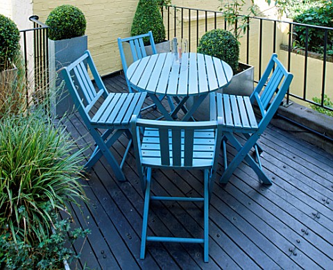 ROOF_GARDEN_DESIGNED_BY_STEPHEN_WOODHAMS_DECKED_TERRACE_WITH_BLUE_TABLE_AND_CHAIRS_AND_METAL_CONTAIN