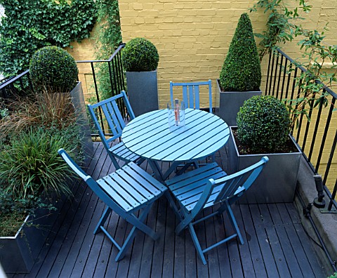 ROOF_GARDEN_DESIGNED_BY_STEPHEN_WOODHAMS_DECKED_TERRACE_WITH_BLUE_TABLE_AND_CHAIRS__YELLOW_PAINTED_W