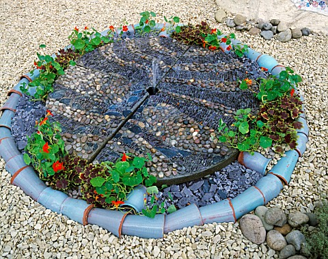 SPANISH_STYLE_GARDEN_WITH_GRAVEL_AND_WATER_FEATURE_MADE_FROM_PEBBLES__NASTURTIUMSAND_PLANT_POTS_THE_
