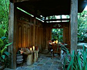 INSIDE OF THE INDONESIAN GAZEBO WITH TABLE AND CHAIRS  CANDLES AND WOODEN HAND SEATS. DESIGNERS: ILGA JANSONS AND MIKE DRYFOOS