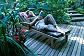 MIKE DRYFOOS RELAXES ON THE DECK BESIDE THE KOI POND. DESIGNERS: ILGA JANSONS AND MIKE DRYFOOS  SEATTLE  USA