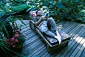 MIKE DRYFOOS RELAXES ON THE DECK BESIDE THE KOI POND. DESIGNERS: ILGA JANSONS AND MIKE DRYFOOS  SEATTLE  USA