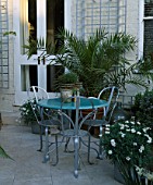 SMALL GARDEN WITH ITALIAN HARD LIMESTONE FLOOR  BLUE TABLE  METAL CHAIRS AND WHITE MARGUERITES. DESIGNER: LISETTE PLEASANCE