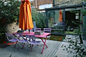 BLUE CAFE CHAIRS  PINK WOODEN TABLE  ORANGE PARASOL  DECKING AND GALVANISED TRAY PLANTED WITH SUCCULENTS: DESIGNER: STEPHEN WOODHAMS