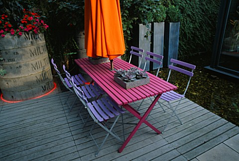 BLUE_CAFE_CHAIRS__PINK_WOODEN_TABLE__ORANGE_PARASOL__DECKING_AND_POOL__DESIGNER_STEPHEN_WOODHAMS