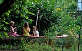 CHILDREN PLAYING IN AN OLD BOAT IN ROSEMARY PEARSONS GARDEN  READING