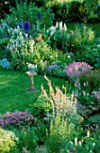 LAUNA SLATTERS GARDEN OXFORDSHIRE: BORDER BESIDE POND WITH LAWN AND SUNDIAL  PLANTED WITH HEBE RAKAIENSIS  PHUOPSIS STYLOSA  VERBASCUM AND LYCHNIS FLOS - JOVIS