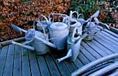 METAL WATERING CANS OUTSIDE THE CONSERVATORY IN WINTER  AT THE LANCE HATTATT DESIGN GARDEN AT ARROW COTTAGE  HEREFORDSHIRE