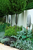 SANCTUARY GARDEN SPONSORED BY MERRILL LYNCH AT THE CHELSEA FLOWER SHOW 2002: DESIGNED BY STEPHEN WOODHAMS: THE FIVE FACE SCULPTURES BY STEPHEN COX WITH CARPINUS BETULUS