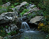 WATERFALL OVER SLATE BOLDERS WITH MEADOW PLANTING IN VISIONS OF SNOWDON GARDEN DESIGNED BY PETER TINSLEY