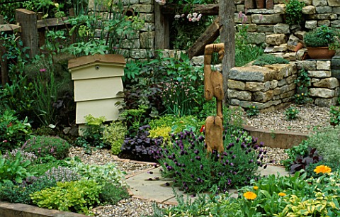 VIEW_ACROSS_HERB_SOCIETYS_GARDEN__CHELSEA_2003_CHIVES_SURROUND_CENTRAL_WOODEN_FEATURE_BY_JON_EDGAR_W