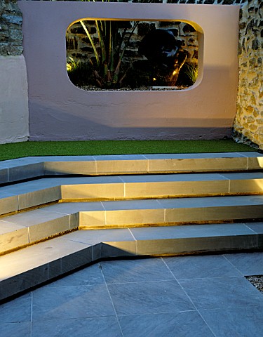 STEPS_AND_RENDERED_CONCRETE_APERTURE_WITH_JELLY_PALM_BUTIA_CAPITATA_AND_SCULPTURE_LIT_UP_AT_NIGHT_IN