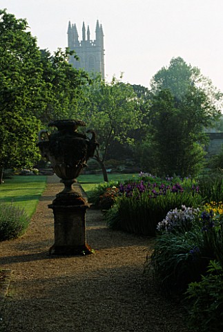 OXFORD_BOTANIC_GARDEN_THE_BOG_GARDEN_WITH_STONE_URN_AND_IRISES_WITH_MAGDALEN_COLLEGE_IN_THE_BACKGROU