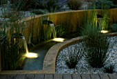WATER FEATURE: GRAVEL GARDEN WITH WATER RILL   RENDERED CONCRETE WALLS AND THREE SPOUTS LIT UP AT NIGHT. DESIGNER: MARK LAURENCE