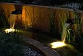 WATER FEATURE: GRAVEL GARDEN WITH WATER RILL   RENDERED CONCRETE WALLS AND SPOUTS LIT UP AT NIGHT. DESIGNER: MARK LAURENCE