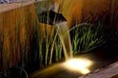 WATER FEATURE: RENDERED CONCRETE WATER RILL WITH SPOUT LIT UP AT NIGHT. DESIGNER: MARK LAURENCE