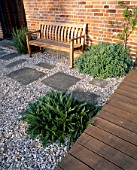 GRAVEL GARDEN BESIDE THE HOUSE WITH WOODEN BENCH  WOODEN DECKING AND STEPPING STONES. DESIGNER: MARK LAURENCE