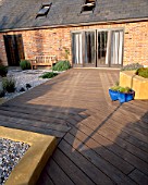GRAVEL GARDEN BESIDE THE HOUSE WITH WOODEN BENCH  WOODEN DECKING AND STEPPING STONES. DESIGNER: MARK LAURENCE