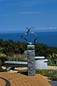 SEASIDE GARDEN  GUERNSEY: VIEW OUT TO SEA WITH BRICK PATIO  GRAVEL  CHINESE GRANITE SEAT  AND SEAGULLS SCULPTURE BY GUY PORTELLI