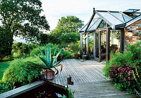 VIEW_OF_DECK_WITH_POOL__AGAVE_AMERICANA_IN_CONTAINER_AND_GARDEN_ROOM_BEHIND_THE_FOVANT_HUT__WILTSHIR