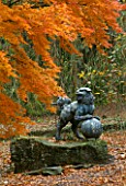 BATSFORD ARBORETUM  GLOUCESTERSHIRE: BRONZE FOO DOG ON A CLOISONNE ENAMEL GLOBE SURROUNDED BY AN ACER PALMATUM IN AUTUMNAL SHADES